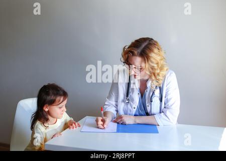 Sorridente scolaresca bambino parlare con medico femminile a consultazione in clinica. Foto Stock