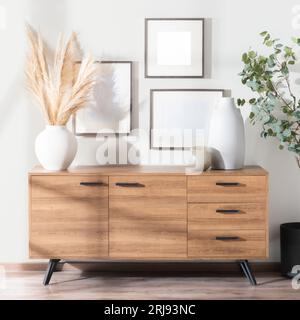 Una credenza in legno con tre vasi e cornici in ceramica appesi alla parete Foto Stock