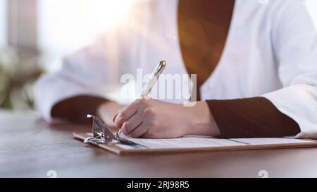 Medico professionista femminile prendere appunti in rivista medica. Foto Stock