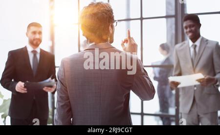 un uomo si alza con la schiena sullo sfondo dei suoi colleghi Foto Stock