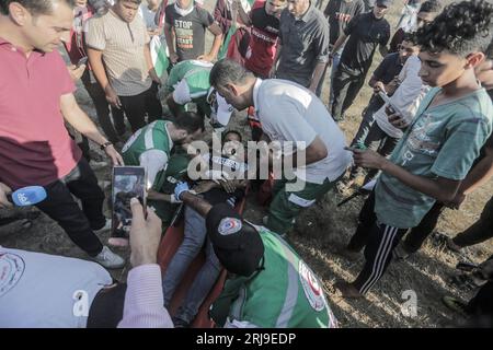 Gaza, Palestina. 21 agosto 2023. I medici evacuano un giornalista ferito durante gli scontri con le truppe israeliane. Centinaia di palestinesi hanno manifestato vicino alla recinzione di confine con Israele. Il Ministero della salute di Gaza ha detto che almeno otto persone sono state ferite dal fuoco israeliano e dal gas lacrimogeno. Credito: SOPA Images Limited/Alamy Live News Foto Stock