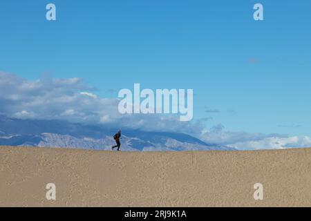 Donna che corre sulla duna di sabbia nel parco nazionale della Death Valley Foto Stock