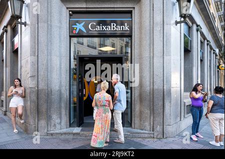 Madrid, Spagna. 21 agosto 2023. I clienti attendono fuori da una filiale per utilizzare un bancomat presso la più grande banca di risparmio spagnola Caixa Bank (CaixaBank) in Spagna. Credito: SOPA Images Limited/Alamy Live News Foto Stock