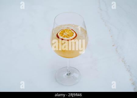 Foto selettiva di Ice Tropical Sangria o Orange cocktail con soda sul bicchiere di vino sul tavolo in marmo bianco Foto Stock