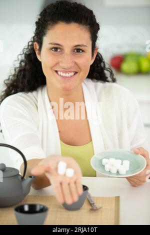 donna felice che tiene la cubetta di zucchero in mano Foto Stock