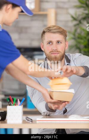 uomo d'affari che riceve la consegna del cibo in ufficio Foto Stock