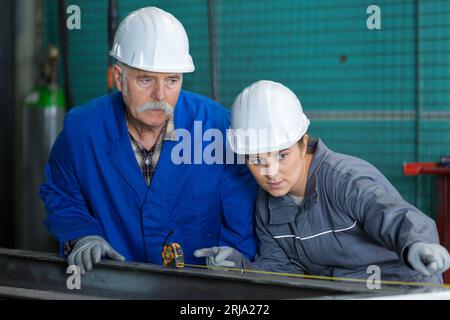 ingegneri che utilizzano un metro a nastro con un supervisore senior Foto Stock