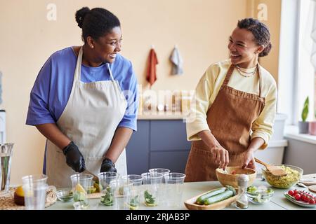 Ritratti in vita di due giovani donne sorridenti che si divertono a cucinare insieme Foto Stock