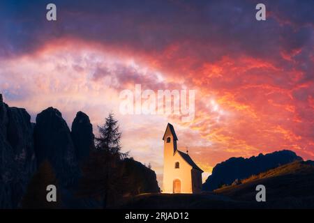 Incredibile vista sulla piccola cappella iIlluminated - Kadelle Ciapela sul Passo Gardena, Dolomiti Italiane. Tramonto colorato nelle Alpi dolomitiche, Italia. Fotografia di paesaggio Foto Stock