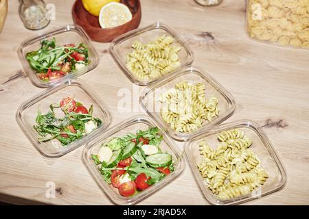 Immagine di sfondo di contenitori di plastica con porzioni di cibo su un bancone in legno della cucina, preparazione dei pasti Foto Stock