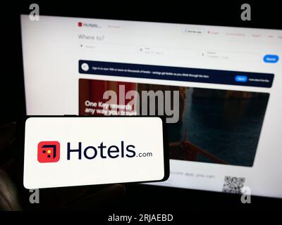 Person holding cellphone with logo of US hotel booking company Hotels.com LP on screen in front of business webpage. Focus on phone display. Stock Photo