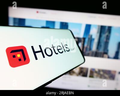 Telefono cellulare con logo della società di prenotazione alberghiera americana Hotels.com LP sullo schermo di fronte al sito web. Mettere a fuoco il display centrale sinistro del telefono. Foto Stock