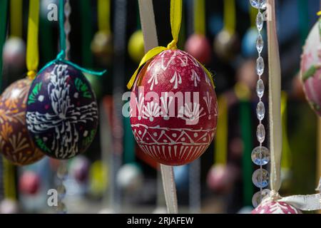 Le uova dipinte pendono dai rami dell'albero di Pasqua. Il fuoco è su un uovo giallo dipinto dai bambini a mano. Foto di alta qualità Foto Stock