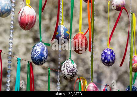 Le uova dipinte pendono dai rami dell'albero di Pasqua. Il fuoco è su un uovo giallo dipinto dai bambini a mano. Foto di alta qualità Foto Stock