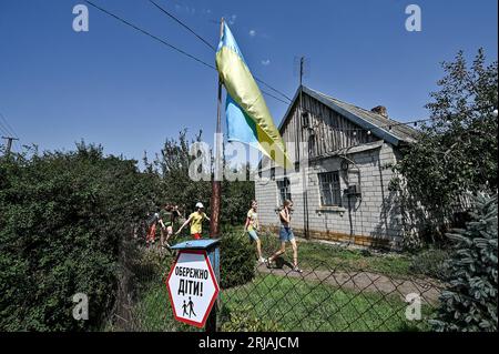 ZAPORIZHZHIA REGIONE, UCRAINA - 21 AGOSTO 2023 - Una bandiera Ucraina è attaccata alla recinzione con i bambini Be careful! Firmi alle api e sta Foto Stock