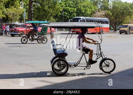 L'Avana, Cuba, Un cubano lavora come autista di pedicab o bicitaxi. Pedala nel quartiere del centro. Foto Stock