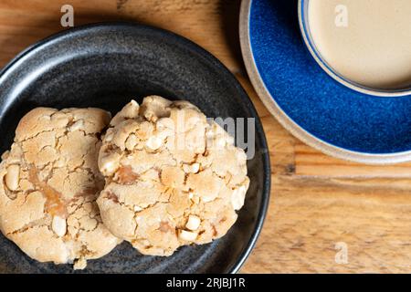 Due biscotti al cioccolato fatti in casa al burro di arachidi di New York serviti su un tavolo a casa con una tazza di caffè fresco. Foto Stock