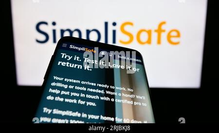 Telefono cellulare con sito Web della società statunitense SimpliSafe Inc. Sullo schermo davanti al logo aziendale. Mettere a fuoco in alto a sinistra sul display del telefono. Foto Stock