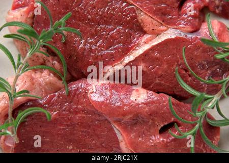 Vista dall'alto della carne rossa. La bistecca tagliata gira su uno sfondo di legno. Spianatura piatta. Carne cruda fresca con spezie ed erbe aromatiche. Black Angus prime Meat St Foto Stock