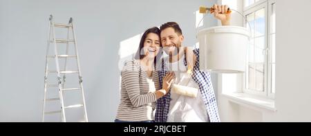 Felice giovane coppia di famiglia che sta ristrutturando e dipingendo i muri della loro casa insieme Foto Stock