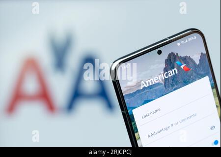 New York, USA - 20 agosto 2023: Primo piano della prenotazione di un volo nell'app della compagnia aerea americana sullo schermo dello smartphone con sfondo sfocato del logo Foto Stock