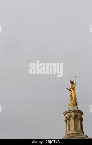 La statua dorata della Vergine Maria in cima alla cattedrale del Palais des Papes (Palazzo dei Papi), ad Avignone, Vaucluse, Francia, in un giorno coperto Foto Stock