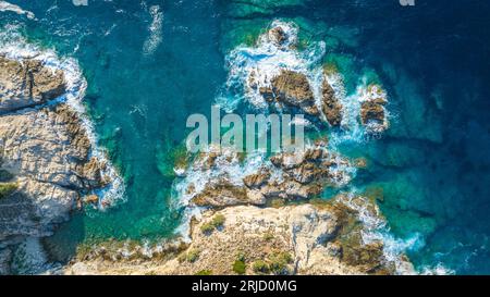 Vista dall'alto delle onde che si infrangono sulla costa rocciosa Foto Stock