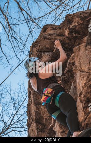 Una donna si sta arrampicando all'aperto nella Pennsylvania occidentale, il suo viso determinato mentre pende da una corda Foto Stock