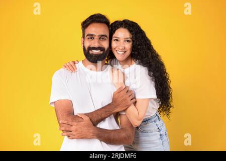 Ritratto di giovani sposi arabi che si abbracciano su sfondo giallo Foto Stock