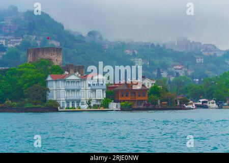 Stanbul, Turchia, 10 maggio 2014: Splendidi edifici sulla riva dello stretto del Bosforo nella città di Istanbul e barche da crociera che navigano nelle piogge giornate primaverili Foto Stock