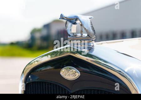 Waltershausen, Germania - 10 giugno 2023: Sul cofano della Ford Model A è presente una statuetta in metallo di una colomba accanto al logo aziendale. Vista frontale, primo piano. Foto Stock