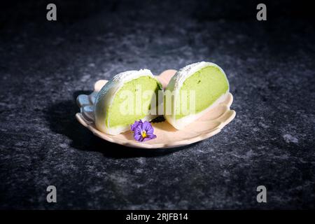 Alta angolazione di tè verde mochi dolce tradizionale giapponese servito su piatto con fiori viola Foto Stock