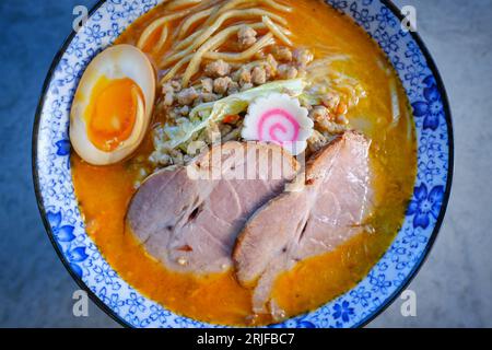 Dall'alto di maiale alla siu in zuppa asiatica con uova sode e tagliatelle di grano in ciotola servite a tavola Foto Stock