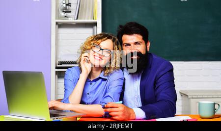 Torna a scuola. Giornata degli insegnanti. Coppia di insegnanti sorridenti al college in classe. Insegnante uomo e donna nel campus universitario. Istruzione e apprendimento Foto Stock