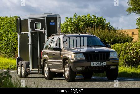 Woburn,Beds.UK - 19 agosto 2023: 1999 Bronze V8 Chrysler Jeep Grand Cherokee che trainano un rimorchio trainato da cavalli su una strada di campagna inglese. Foto Stock