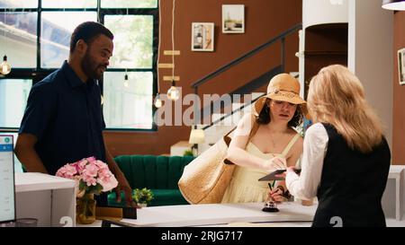 I turisti si registrano alla reception, utilizzando un tablet per firmare i moduli elettronici. Coppia in luna di miele compilando i documenti di registrazione per il processo di check-in della prenotazione. Scatto manuale. Foto Stock