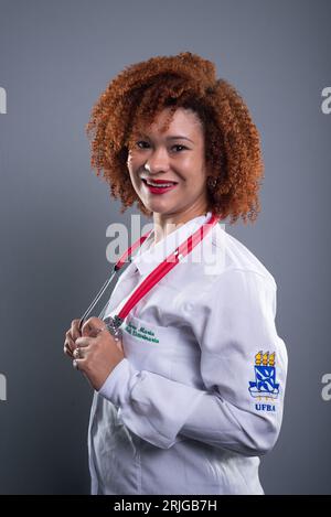 Giovane graziosa studentessa di medicina veterinaria dai capelli rossi in posa per una foto in camice bianco. Concetto di cura degli animali. Foto Stock