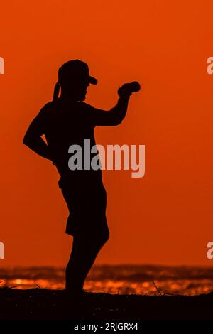 Isola di Palms, Stati Uniti. 22 agosto 2023. Un uomo esercita sulla spiaggia sagomata dall'alba come cupola di calore nel sud porta il clima caldo e umido nella zona di Charleston, il 22 agosto 2023 a Isle of Palms, South Carolina. Crediti: Richard Ellis/Richard Ellis/Alamy Live News Foto Stock