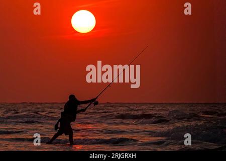 Isola di Palms, Stati Uniti. 22 agosto 2023. Un pescatore si getta nell'Oceano Atlantico sagomato dall'alba mentre una cupola di calore attraverso il sud porta il clima caldo e umido nella zona di Charleston, il 22 agosto 2023 a Isle of Palms, South Carolina. Crediti: Richard Ellis/Richard Ellis/Alamy Live News Foto Stock