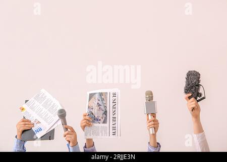 Mani femminili con giornali e microfoni su sfondo chiaro Foto Stock