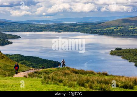 Escursionisti e escursionisti che scendono da Conic Hill con vista su Balmaha e Loch Lomond nelle Highlands scozzesi. Foto Stock