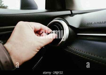 La mano del conducente regola la direzione del vento della bocchetta di ventilazione della vettura, regolazione della direzione del pulsante dell'impianto di climatizzazione della vettura, Automoti Foto Stock