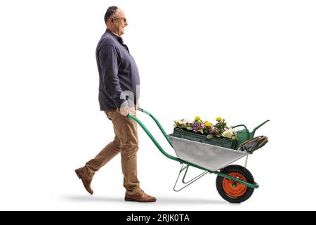 Foto a profilo completo di un uomo maturo che spinge una carriola con fiori isolati su sfondo bianco Foto Stock
