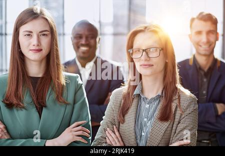 orgoglioso gruppo professionale diversi uomini d'affari in piedi in ufficio con le braccia incrociate Foto Stock