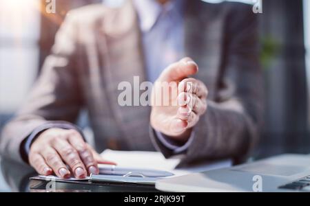 Un uomo saluta un collega e si offre di sedersi in ufficio Foto Stock