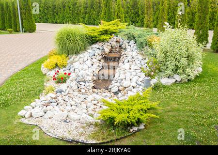 Una passerella con giardino fiancheggiata da grandi pietre e fogliame, che crea una splendida area all'aperto nel cortile sul retro Foto Stock