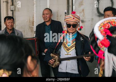 Un gruppo di minoranze etniche nella Cina meridionale si riunì indossando i loro abiti tradizionali e suonando vari strumenti musicali Foto Stock