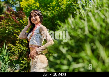 giovane donna indiana in abiti tradizionali sorridente nel parco estivo in primo piano sfocato Foto Stock