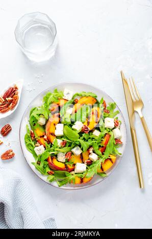 Insalata di pesca alla griglia con formaggio blu, noci pecan e rucola su sfondo luminoso Foto Stock