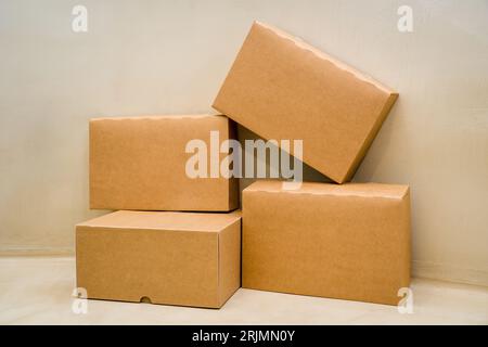 Una pila di scatole di cartone disposte in una pila su uno sfondo di colore beige Foto Stock